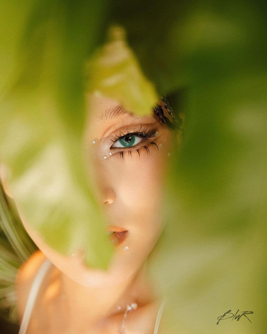 girl behind green bushes with her eye showing
